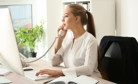 Beautiful female secretary talking on telephone in office