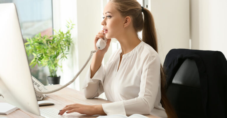 Beautiful female secretary talking on telephone in office