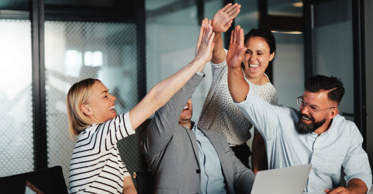 Businesspeople high-fiving at work