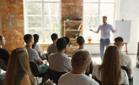 Male speaker giving presentation in hall at university workshop