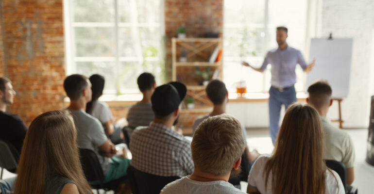 Male speaker giving presentation in hall at university workshop
