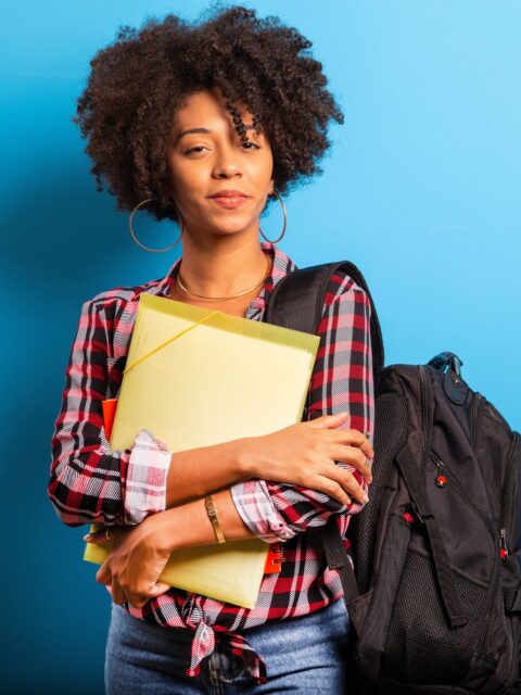 young african student with backpack on the back on blue background